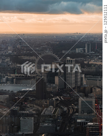 Aerial view of London at sunset with the London Eye, Thames River, and diverse architecture. The cityscape is illuminated by a warm glow during Christmas. Aerial view of London at sunset with the London Eye, Thames River, and diverse architecture. The cityscape is illuminated by a warm glow during Christmas. 125012111