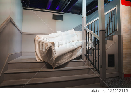A white couch is positioned on a staircase with a wooden railing, part of a Friends themed exhibition in London, replicating a famous TV scene. A white couch is positioned on a staircase with a wooden railing, part of a Friends themed exhibition in London, replicating a famous TV scene. 125012116