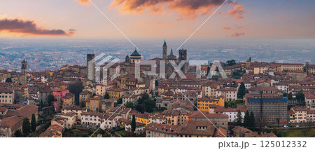 View of Bergamo's old town, Italy, at sunset, featuring the Basilica of Santa Maria Maggiore, medieval bell towers, and terracotta rooftops. View of Bergamo's old town, Italy, at sunset, featuring the Basilica of Santa Maria Maggiore, medieval bell towers, and terracotta rooftops. 125012332