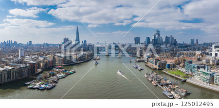 Aerial view of London featuring Tower Bridge over the River Thames, The Shard, Canary Wharf, and historic and modern riverside architecture on a bright day. Aerial view of London featuring Tower Bridge over the River Thames, The Shard, Canary Wharf, and historic and modern riverside architecture on a bright day. 125012495