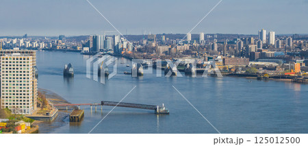 Aerial view of the Thames Barrier on the River Thames in London, surrounded by modern buildings and high rise structures on a clear day. 125012500