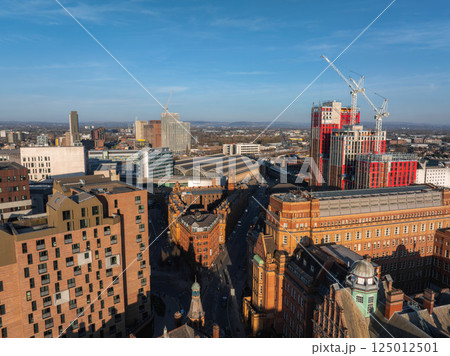 Aerial view of Manchester, UK, on a sunny day with the Manchester Central Convention Complex, modern skyscrapers, and ongoing construction visible. 125012501