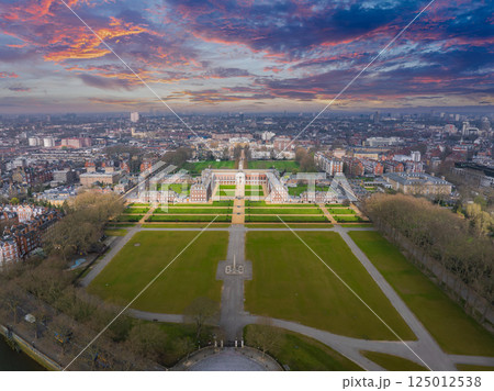 Aerial perspective of the Royal Hospital Chelsea in London, featuring red brick buildings, green lawns, and the urban sprawl under a cloudy sky. 125012538