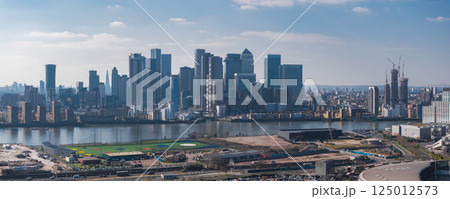 Aerial view of London's Canary Wharf skyline with modern skyscrapers, the River Thames in the foreground, and the Shard visible in the distance. Aerial view of London's Canary Wharf skyline with modern skyscrapers, the River Thames in the foreground, and the Shard visible in the distance. 125012573