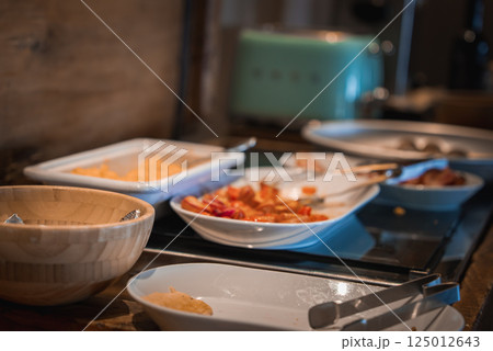 Close up of a breakfast setup featuring sliced fruits, a creamy dish, and a mint green toaster, with wooden elements in a cozy Alpine setting. Close up of a breakfast setup featuring sliced fruits, a creamy dish, and a mint green toaster, with wooden elements in a cozy Alpine setting. 125012643