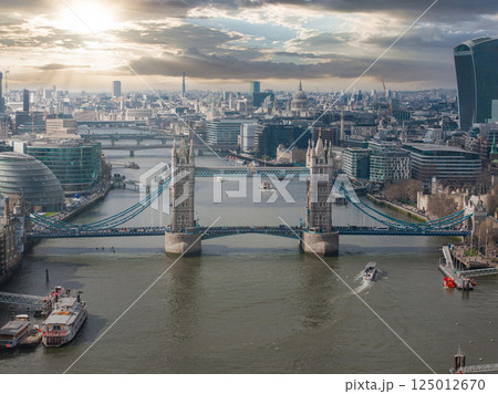 Tower Bridge spans the River Thames with City Hall, the Walkie Talkie, St. Paul's Cathedral, and the Shard visible under a partly cloudy sky. Tower Bridge spans the River Thames with City Hall, the Walkie Talkie, St. Paul's Cathedral, and the Shard visible under a partly cloudy sky. 125012670