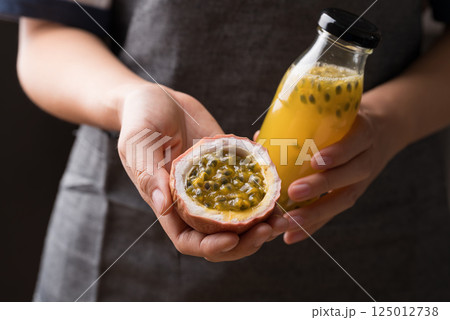 Hand holding fresh passion fruit and bottle of passion fruit juice, Healthy eating 125012738