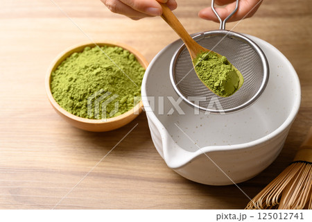 Matcha green tea powder pouring in sieve prepare for tea mixing Matcha green tea powder pouring in sieve prepare for tea mixing 125012741