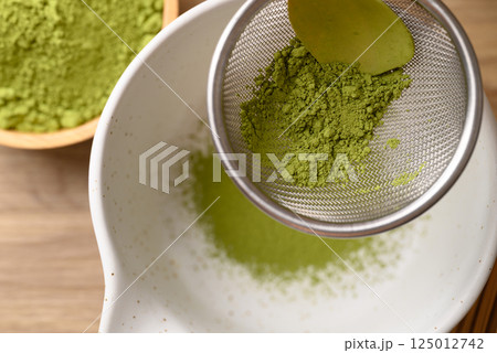 Matcha green tea powder pouring in sieve prepare for tea mixing, Top view Matcha green tea powder pouring in sieve prepare for tea mixing, Top view 125012742
