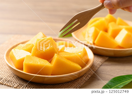 Sliced mango on wooden plate ready to eating, Tropical fruit in summer season Sliced mango on wooden plate ready to eating, Tropical fruit in summer season 125012749