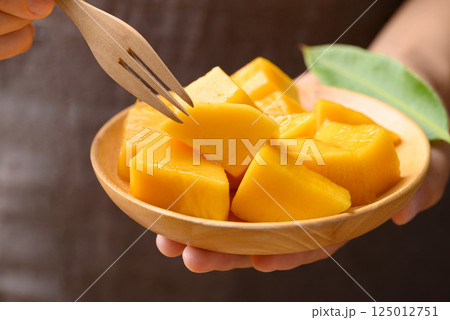 Sliced mango on wooden plate holding by hand ready to eating, Tropical fruit in summer season Sliced mango on wooden plate holding by hand ready to eating, Tropical fruit in summer season 125012751