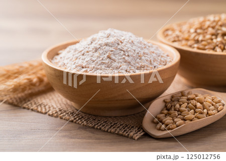 Whole wheat flour with wheat grain in bowl on wooden background 125012756