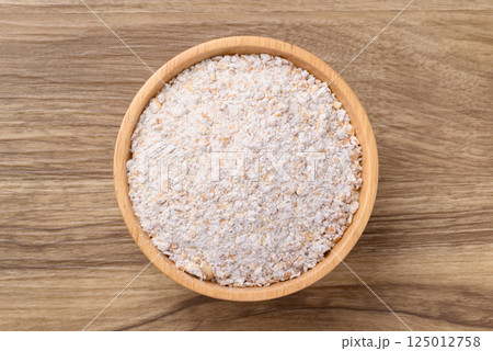 Whole wheat flour in bowl on wooden background, Table top view 125012758