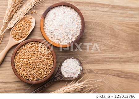 Whole wheat flour with wheat grain in bowl on wooden background, Table top view 125012760