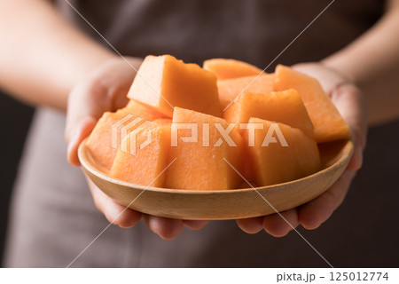 Sliced Orange melon, Musk melon or Flesh melon on plate holding by hand ready to eating 125012774