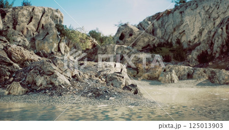 Rocky shoreline near tranquil water under a clear sky during daytime Rocky shoreline near tranquil water under a clear sky during daytime 125013903