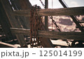 Rusted chains hanging on weathered wooden beams in an abandoned structure 125014199