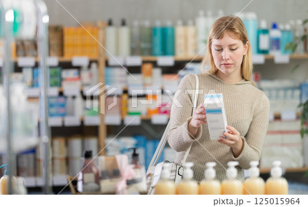 Girl in autumn clothes buys medicinal ointment at pharmacy Girl in autumn clothes buys medicinal ointment at pharmacy 125015964