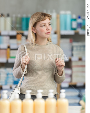 Portrait of girl in autumn clothes shopper choosing some products in supermarket Portrait of girl in autumn clothes shopper choosing some products in supermarket 125016062