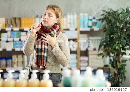 Young woman with sore throat at pharmacy 125016197