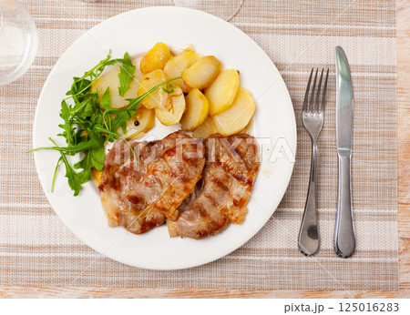 Fried pork served with potatoes and arugula Fried pork served with potatoes and arugula 125016283
