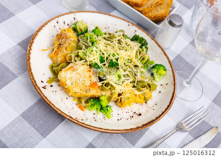 Authentic Italian fettuccine pasta dish with chicken breast and broccoli on table 125016312