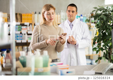 Woman with mobile phone on pharmacist background 125016314