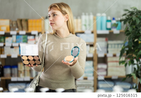 Young girl choosing cosmetics in chemist's shop 125016315