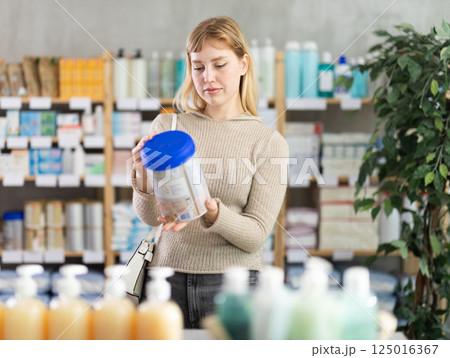 Young woman examines baby food Young woman examines baby food 125016367