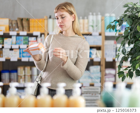 Girl in winter clothes looking for medicine in pharmacy 125016373