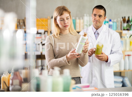 woman chooses a shampoo against the background of a pharmacist 125016396