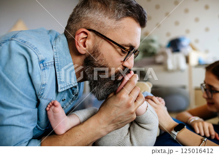 Portrait of father kissing little baby boy's feet. 125016412
