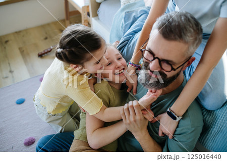 Portrait of father with three daughters at home. 125016440