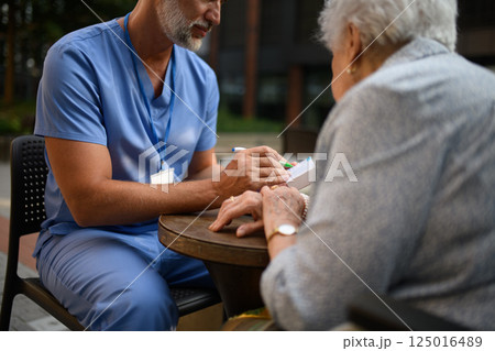 Doctor explaining medication to senior patient and answering her questions. 125016489