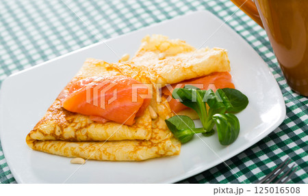 pancakes with slice of smoked salmon and spinach served on white plate 125016508