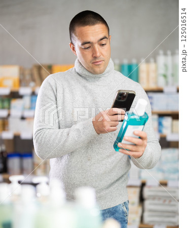 Male buyer scans code on mouthwash to check expiration date 125016514