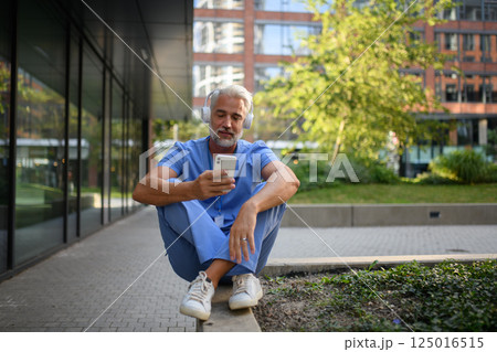 Healthcare worker outside hospital and checking phone during break. 125016515