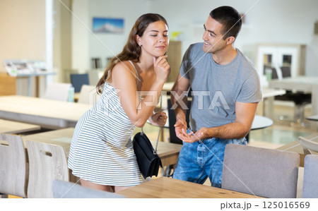 In exhibition furniture hall,spouses choose wooden table In exhibition furniture hall,spouses choose wooden table 125016569