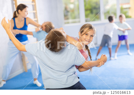 Kids in sportswear exercising self-protection techniques in pair during class 125016613