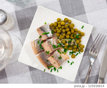 Sliced herring served with scallion and peas on table 125016614