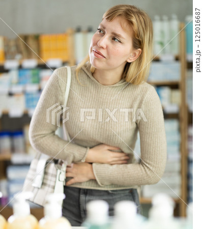 Woman with PMS spasms in pharmacy Woman with PMS spasms in pharmacy 125016687