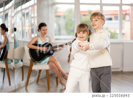 Boy and girl in pair train to dance tango during classes with accompaniment of guitar 125016843
