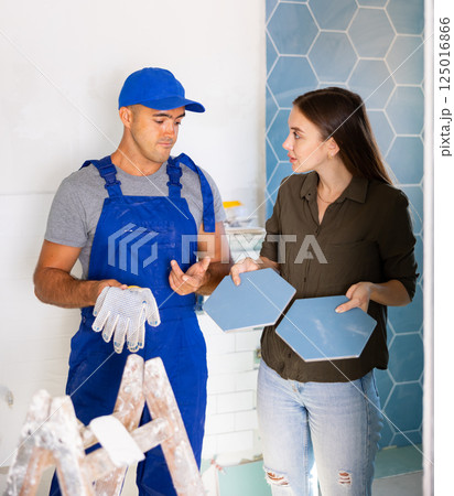 Professional builder gives advice to the landlady on which ceramic tiles to choose for bathroom 125016866