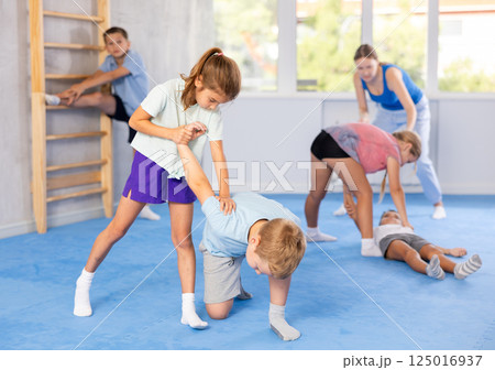 Kids in sportswear exercising self-protection techniques in pair during class 125016937