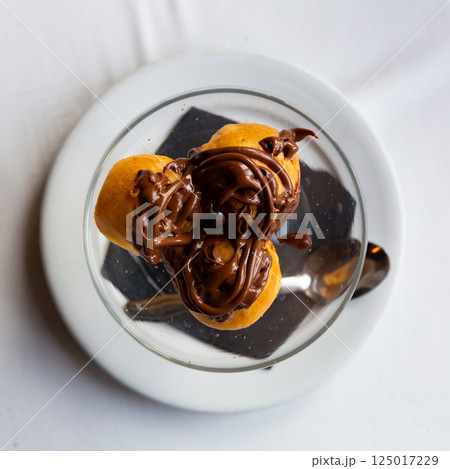 Cream puffs with melted chocolate served on table 125017229