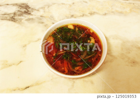 Red borscht with greenery on a light background close-up. National food Red borscht with greenery on a light background close-up. National food 125019353