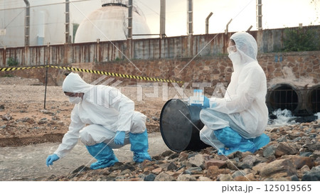 Ecologist sampling water from the river with test tube, Scientist or Biologist in a protective suit and protect mask collects sample of waste water from industrial for analyze, problem environment Ecologist sampling water from the river with test tube, Scientist or Biologist in a protective suit and protect mask collects sample of waste water from industrial for analyze, problem environment 125019565