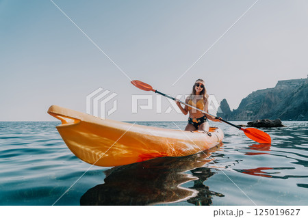 Kayaking Woman Ocean Coastline - Kayaking in the ocean near a rocky coastline on a sunny day. 125019627