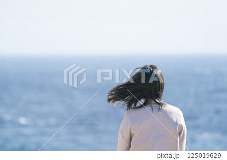 海風に髪を靡かせながら海を眺める女性 125019629