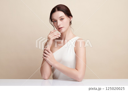 A beautiful young woman with clean, fresh skin against a beige background. Skincare, facial treatment, cosmetology, beauty, and spa. An elegant portrait of an woman. A beautiful young woman with clean, fresh skin against a beige background. Skincare, facial treatment, cosmetology, beauty, and spa. An elegant portrait of an woman. 125020025